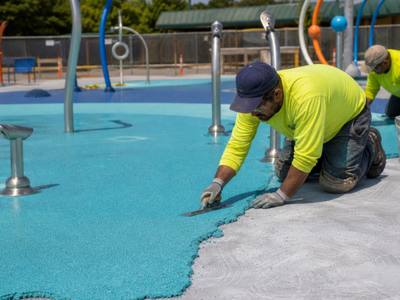 Crew installing rubber surfacing around a splash pad