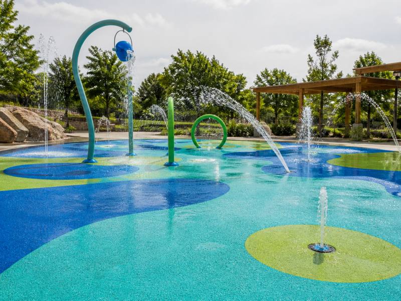 Splash pad on blue and green rubber surfacing with water features spraying